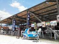 複数の海の家が並び、かき氷と書かれた旗やメニュー看板が掲げられている写真