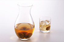 透明なガラス瓶に入った梅酒、氷と梅酒の入ったグラスが並んでいる写真