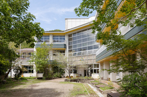 手前に広々とした道がある、窓が広く開放的な建物の写真