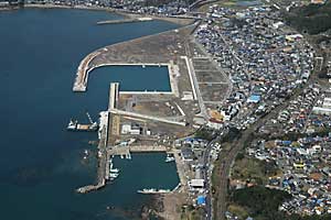 海沿いの港と防波堤が並ぶ町並みを上空から写した写真