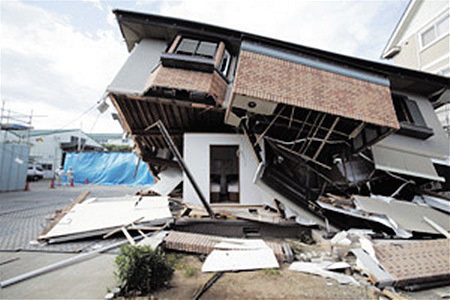 倒壊した家屋の中に箱型のシェルターが設置されている写真