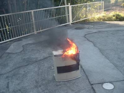 外に置かれた石油ファンヒーターから炎が上がっている写真