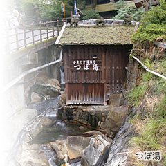 「つぼ湯」と書かれた木製の茶色い看板がある温泉施設の外観の写真