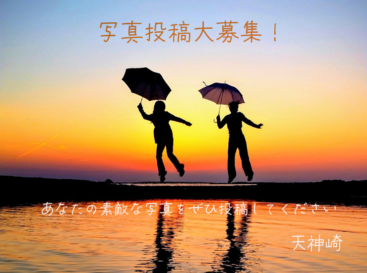 夕焼けに染まる天神崎で、傘を持った2人がジャンプしている写真
