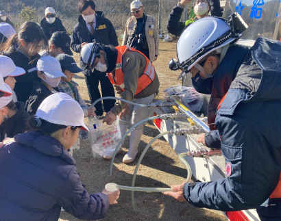 児童達が給水車のホースから水を注いでもらっている写真
