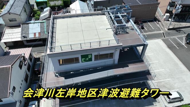 「会津川左岸地区津波避難タワー」と書かれ、住宅の隣に建てられた4階建ての津波避難タワーの写真（YouTubeへリンク）