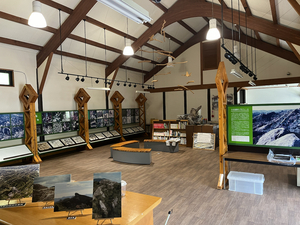 高い天井に木の梁が渡された室内で、壁沿いに写真パネルが並ぶ展示室の写真