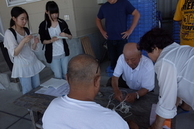 白髪の男性が紐の扱い方を教えている写真