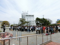 広場に大人数が整列し前に立って話している人の話を聞いている写真