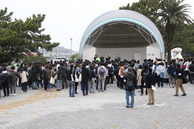 半円形の屋根を持つステージに、多くの人が集まっている写真