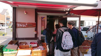 複数の人が並んで青果店へ入ろうとしている写真