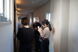 メモを取りながら説明を受けている人と説明をしているマスク姿の男性の写真