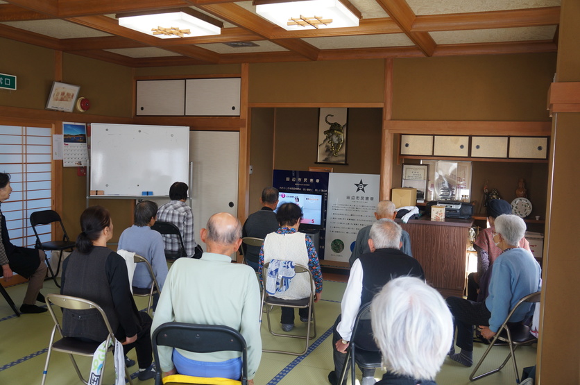 みんなで筋トレ体操の参加者がDVDを見ながら椅子に座って体操をしている写真