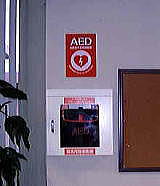 壁にAEDと書かれた赤いシールが貼られその下にある壁に埋め込まれて設置されているAEDの写真