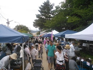 白と青のテントの下にある出店を見ている客の写真