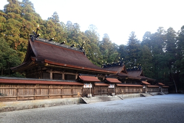 塀と木に囲まれた赤い建物の写真