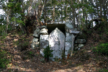木が生い茂る山の中に置かれている地蔵塚の写真