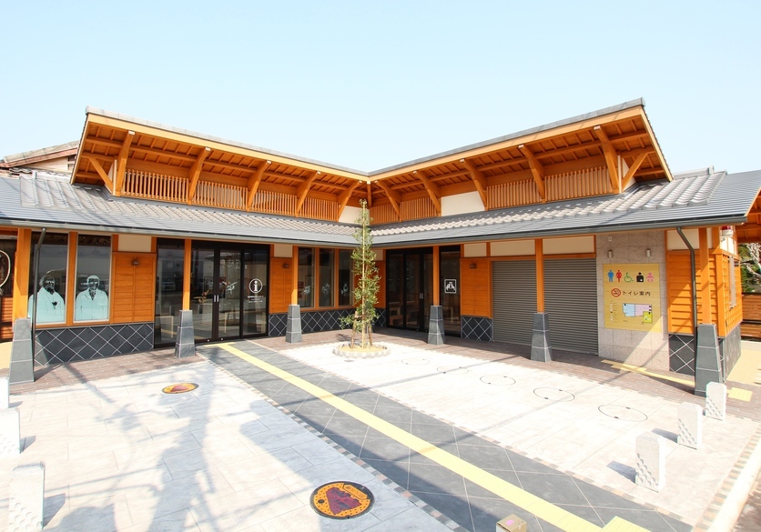 瓦の屋根にオレンジ色の木材が使われたL字型の建物写真