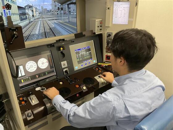 電車の運転席でレバーなどを操縦している男性の写真