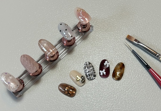 リボンやハートのパーツが付いたネイルチップと筆の写真