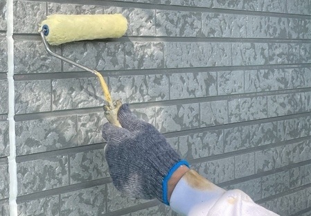 壁にローラーを当てている人の手元の写真