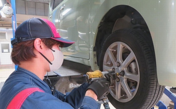 車のタイヤを修理している作業員の写真