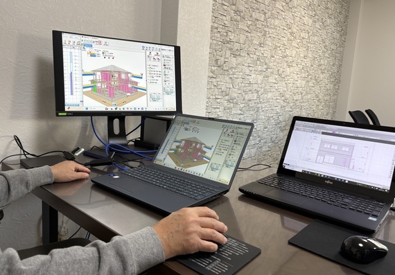 2台のノートパソコンの左わきに1台のモニターが置かれたデスクの写真
