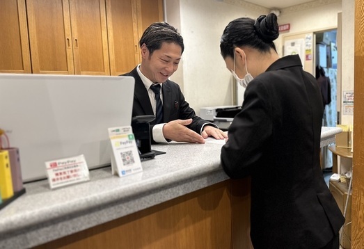 受付カウンターで書類に書き込んでいる女性と説明をする男性の写真