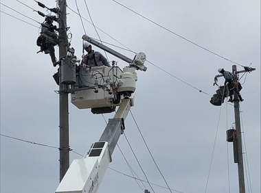 クレーンに乗って電柱の点検作業を行っている作業員たちの写真