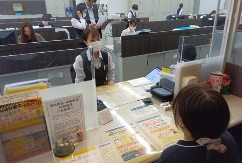 窓口に座っているマスクをした女性職員と話をする女性の写真