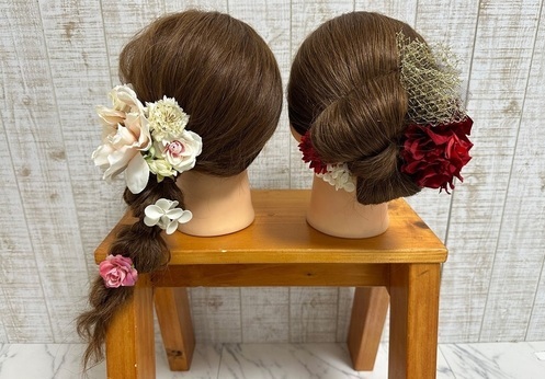 花飾りなどを使用したヘアアレンジが施されたウィッグ2体の写真