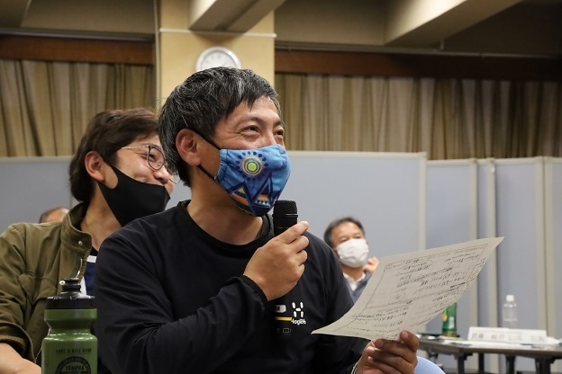 男性が手に紙を持ちながらマイクで話をしている写真