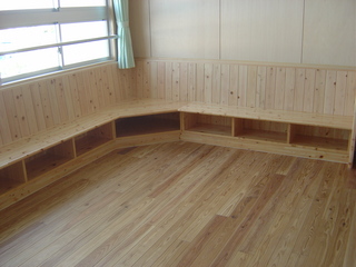 L字の木造ベンチが壁に沿って設置されている写真