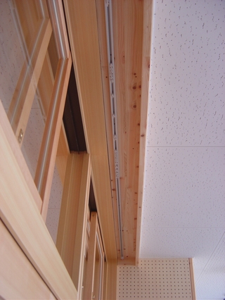 天井の木枠につけられたカーテンを下げる金具の写真