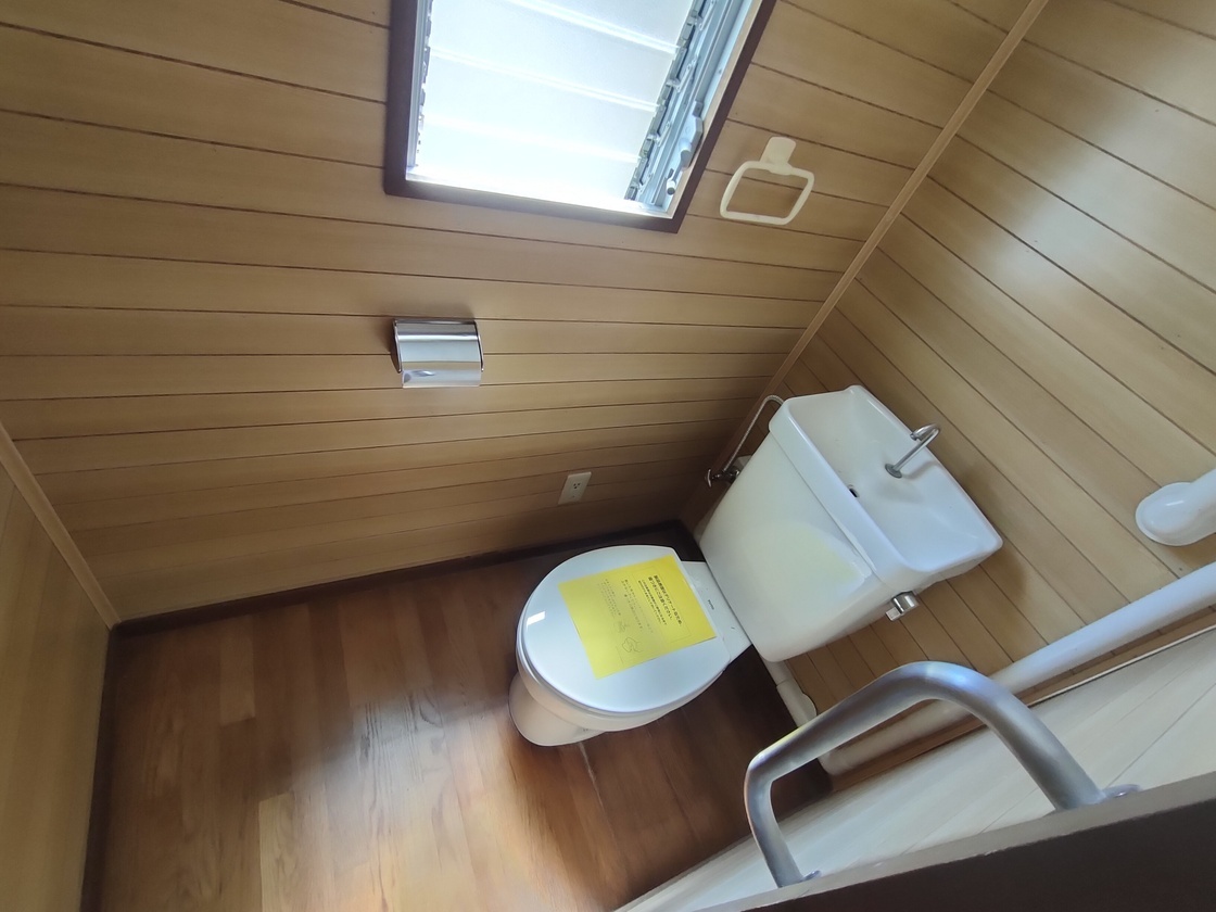 洋式トイレの便器の蓋の上に黄色い紙が置かれている写真