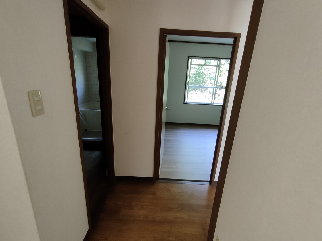 廊下から部屋の窓越しに外が見える写真