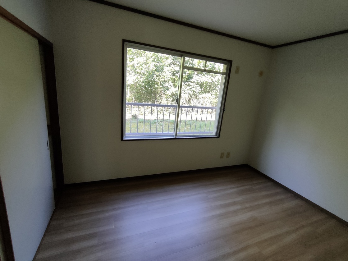 窓から明るい外がうかがえる洋室の写真