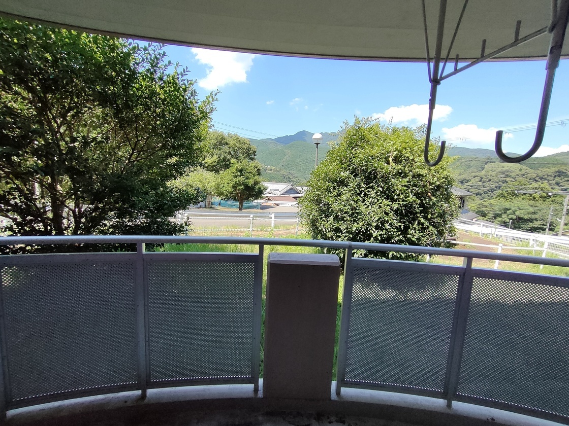 遠くに山や民家が見えるバルコニーの写真