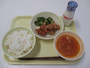 ごはん、きゅうりと唐揚げ、ミネストローネと牛乳が置かれたお盆の写真