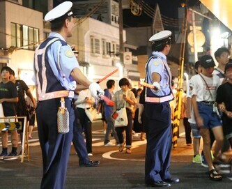 地域の祭りで警察官が通行人の誘導をしている写真