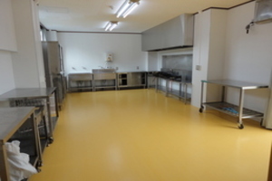 物が隅に置かれ広いスペースがとられた一室の室内の写真