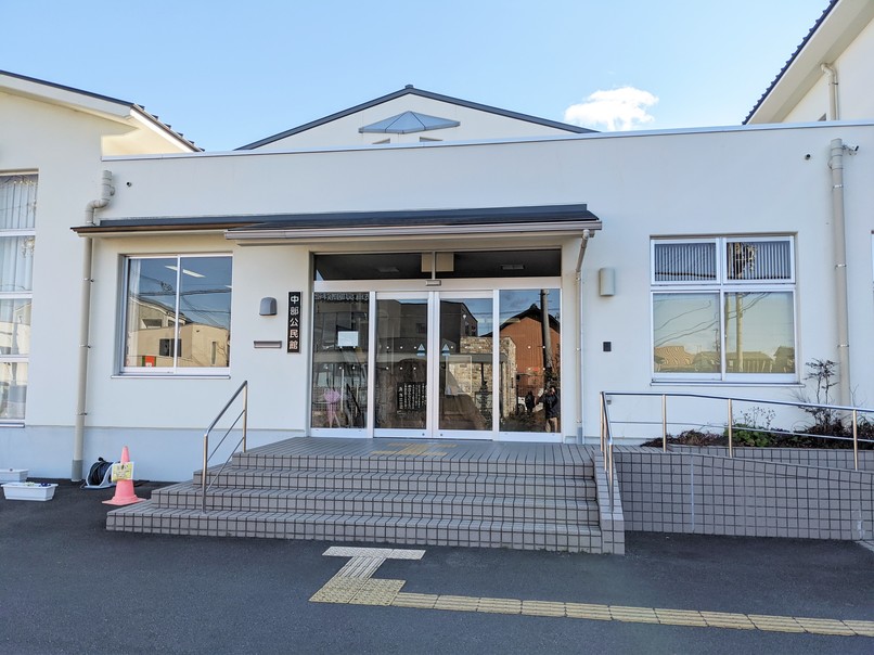 入口前に階段とスロープのある白い外壁の建物の写真