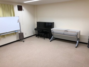 ピアノ、ホワイトボードと折り畳み式テーブルが置かれた部屋の写真