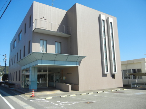 ベージュ色の外壁で3階建ての建物の写真