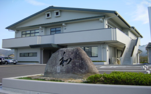 三角屋根の建物の前に「和」と書かれた石が置かれている写真