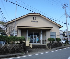 中央に庇と入口のあるベージュ色の外観をした建物の写真