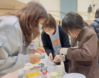 女の子と2人の女性が向かい合って、手元を見ながら作業している写真