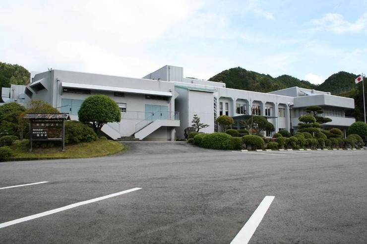 広い駐車場が併設されている白色の大きな建物の写真