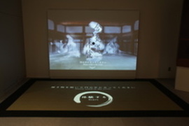 スクリーンが正面と床に設置されて映像を映している写真