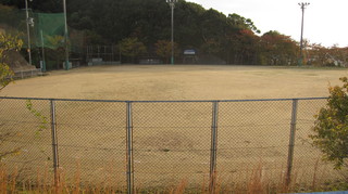 フェンスが設置されている土の屋外グラウンドの写真